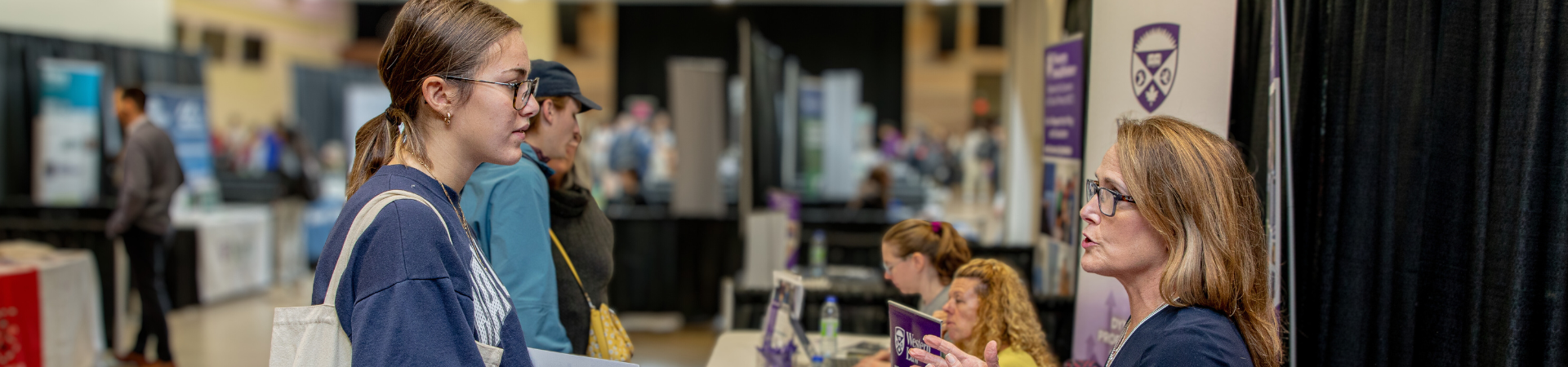 A student engages with a older lady at an event booth.