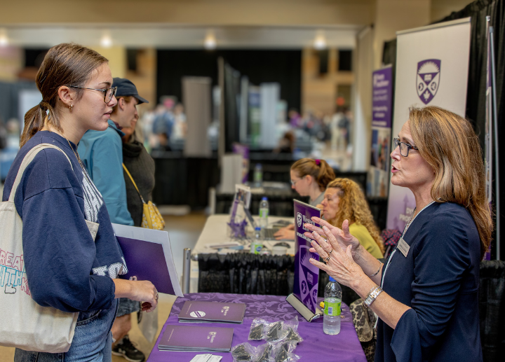 A young woman speaks to an older woman at an event.