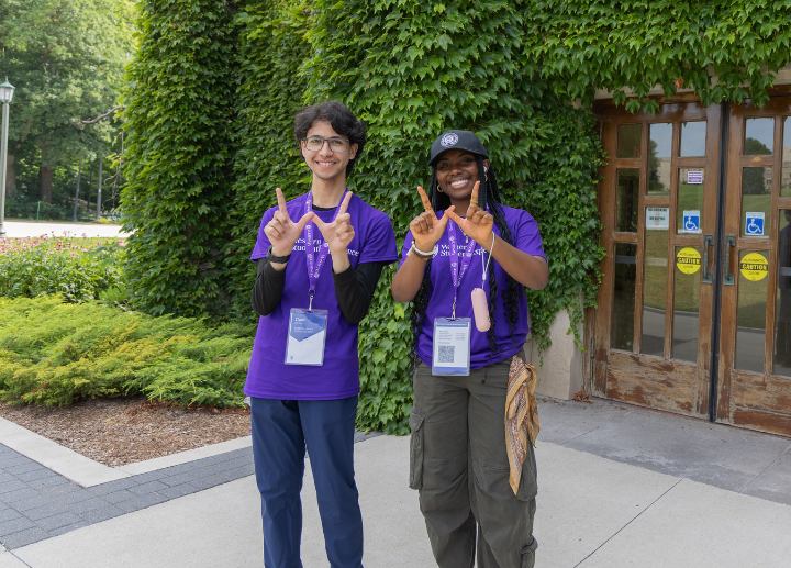 Two students make a W sign with their hands.