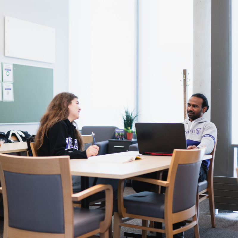 Several students working on laptops in an academic setting.