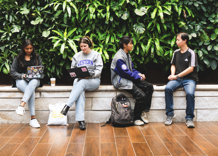 Four students walk outside in front of University College.