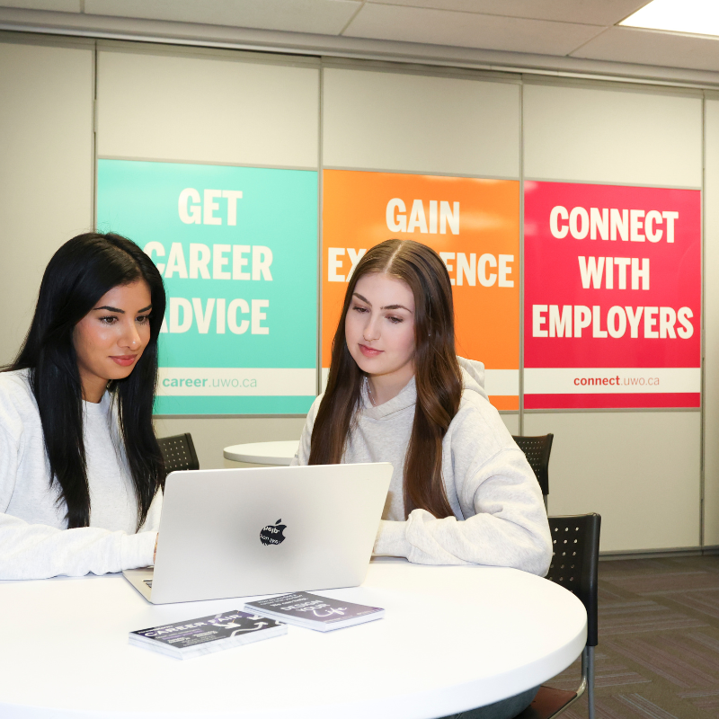 Two students work on a laptop together in a career services office.