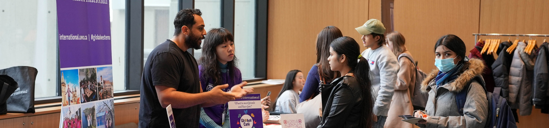 Several students listen to a speaker at an event booth.